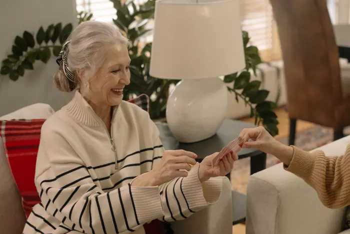 A smiling older woman holding her cards during a relaxed card game at home