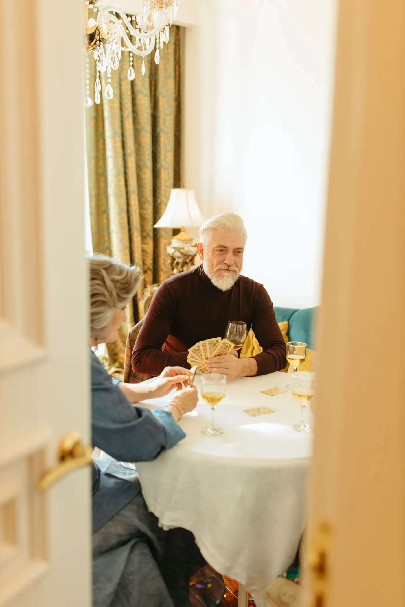 Two older adults enjoying a game of cards together indoors