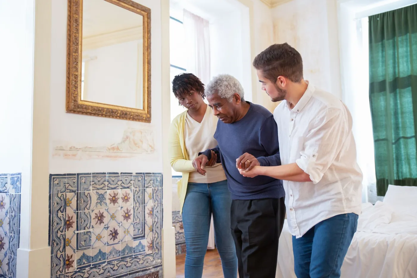 An older man walking through his home with a steadying arm on each side
